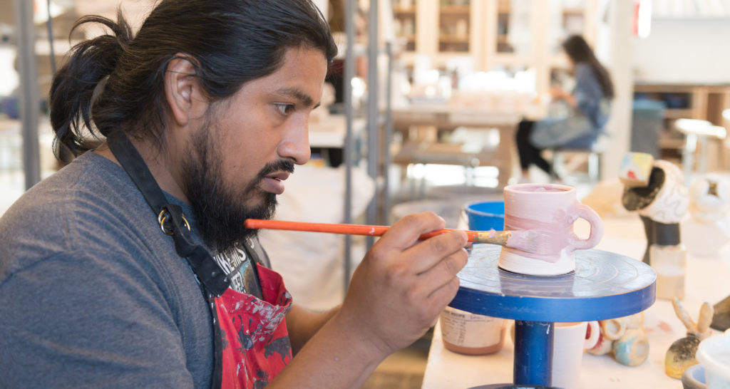 Colorado State University art student Saxon Martinez applies glaze to a cup in Sanam Emami's pottery class, December 4, 2018.