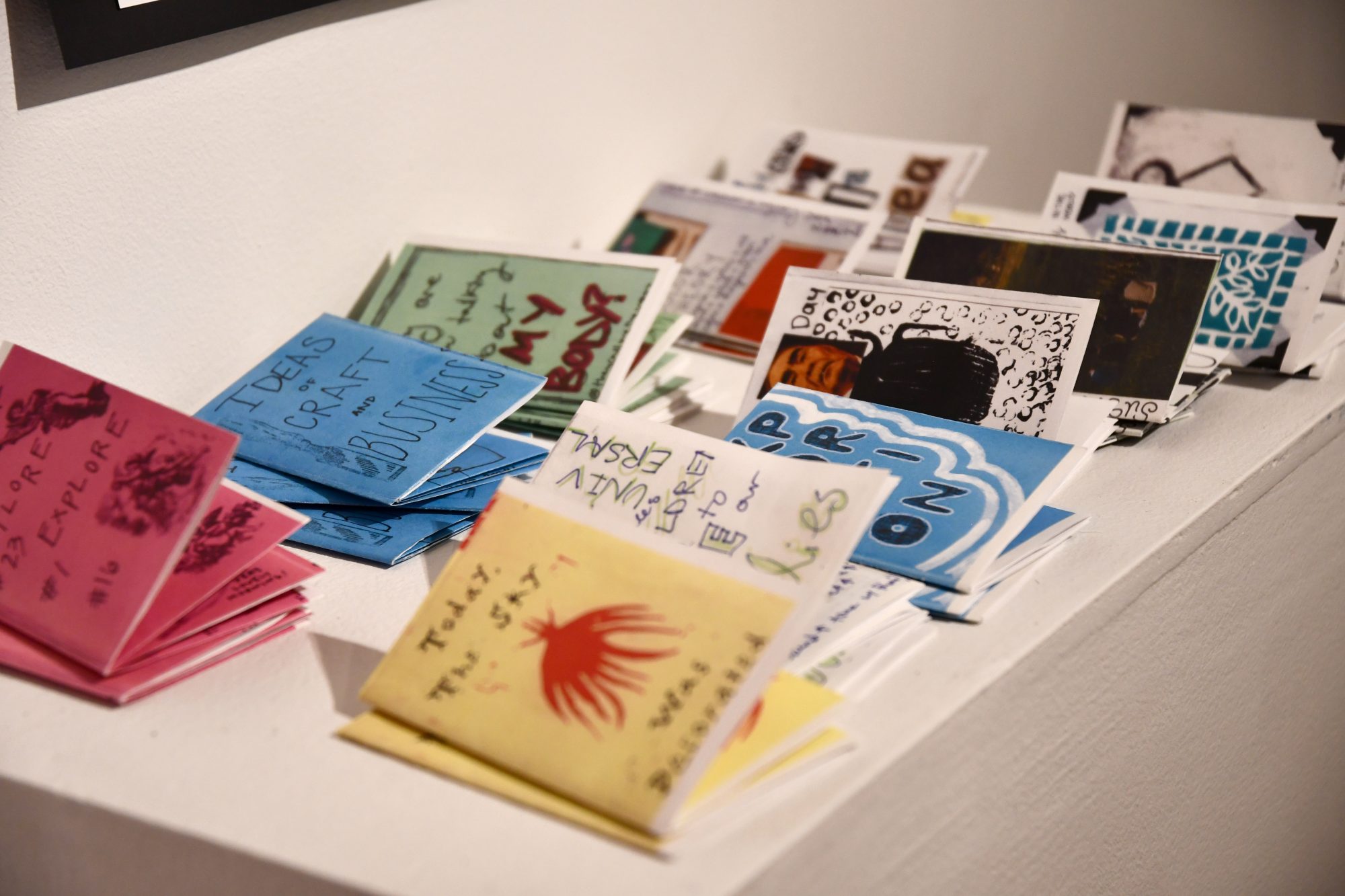 A collection of handmade zines displayed on a white surface.