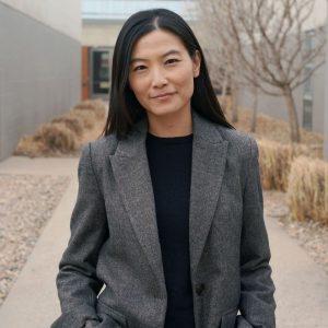 Xinran Yuan standing in front of building wearing a gray jacket and black shirt