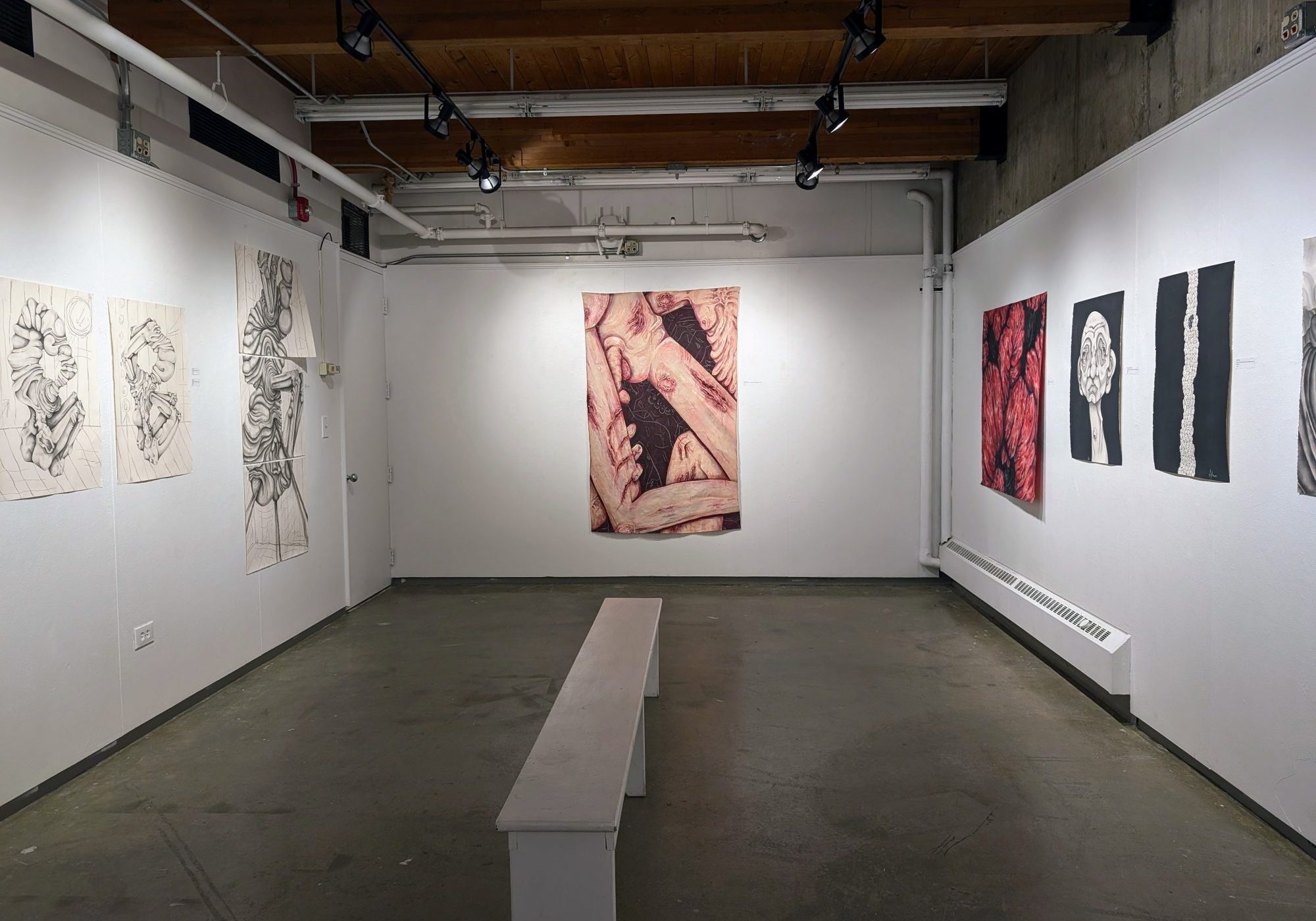 Gallery space with white walls and concrete floor, featuring large-scale drawings and paintings.