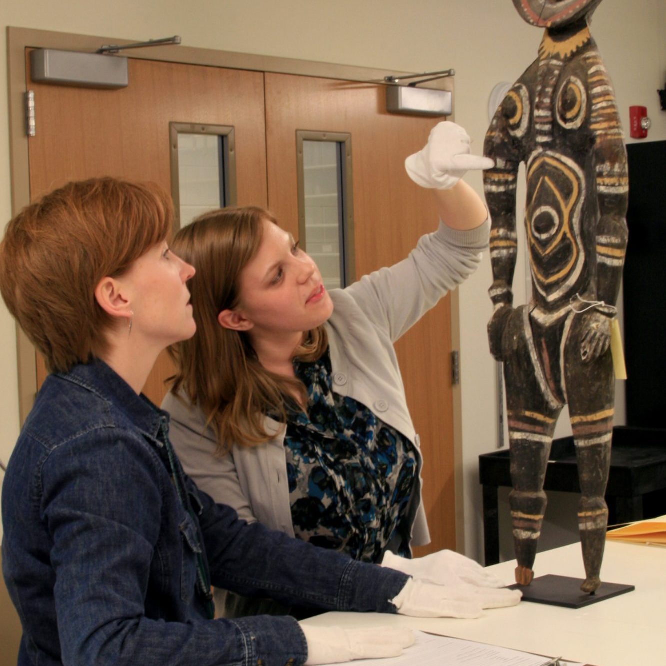 Two students examine an African sculpture
