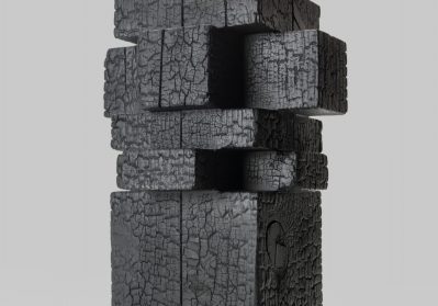 Modern sculpture with a glowing white globe atop stacked black charred wood blocks.